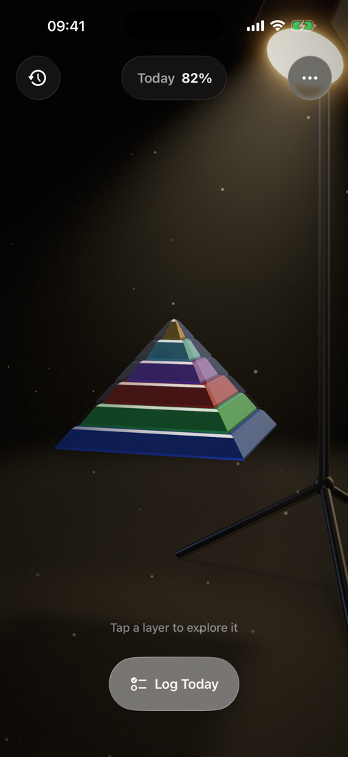 The Maslow pyramid — six colored layers lit by a warm studio projector